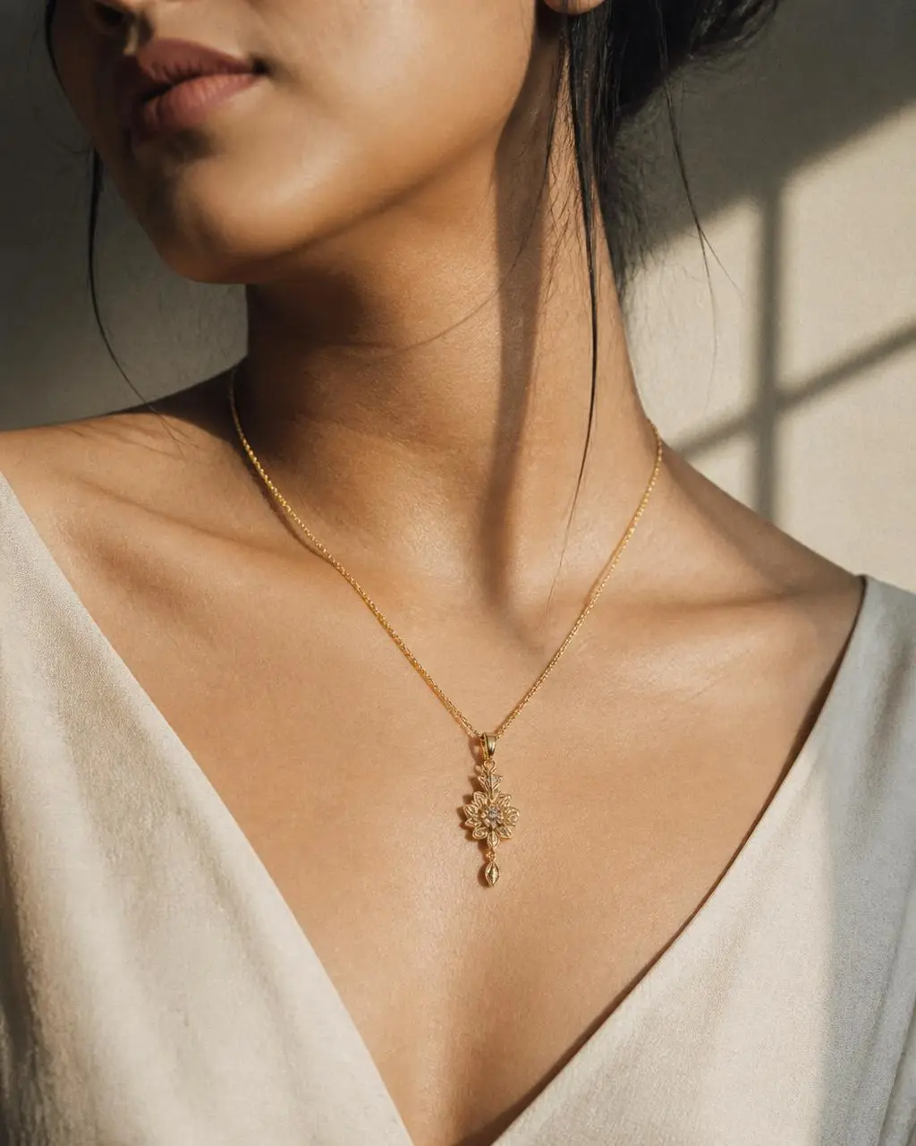 Handmade gold pendant necklace worn at the collarbone