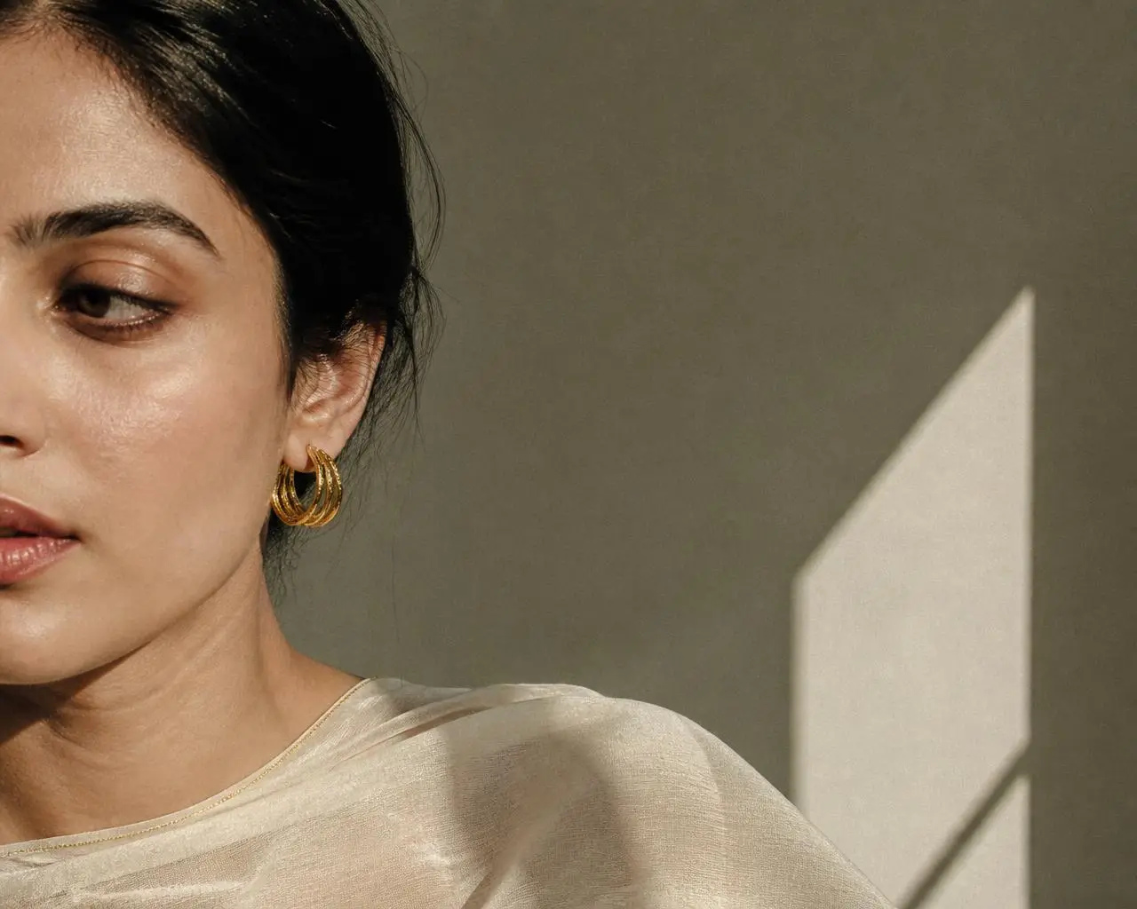 Woman wearing handmade gold hoop earrings in soft daylight